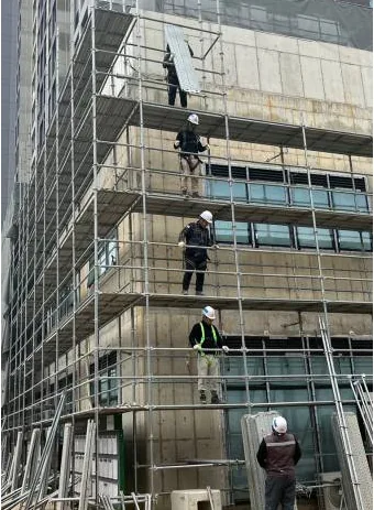 비계 위에서 수작업으로 자재를 옮기는 작업자들의 현장 사진
